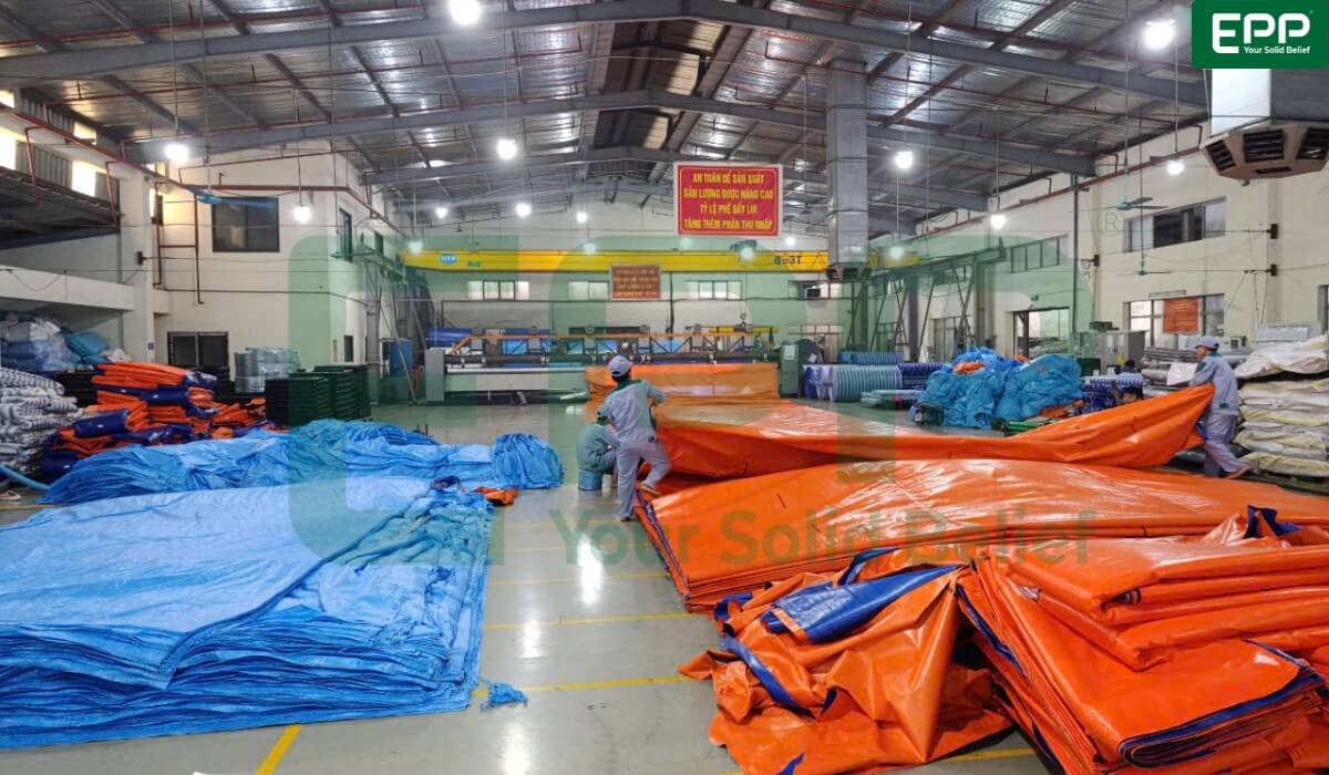 blue and orange heavy-duty PE tarpaulins inside an ISO-certified production factory.